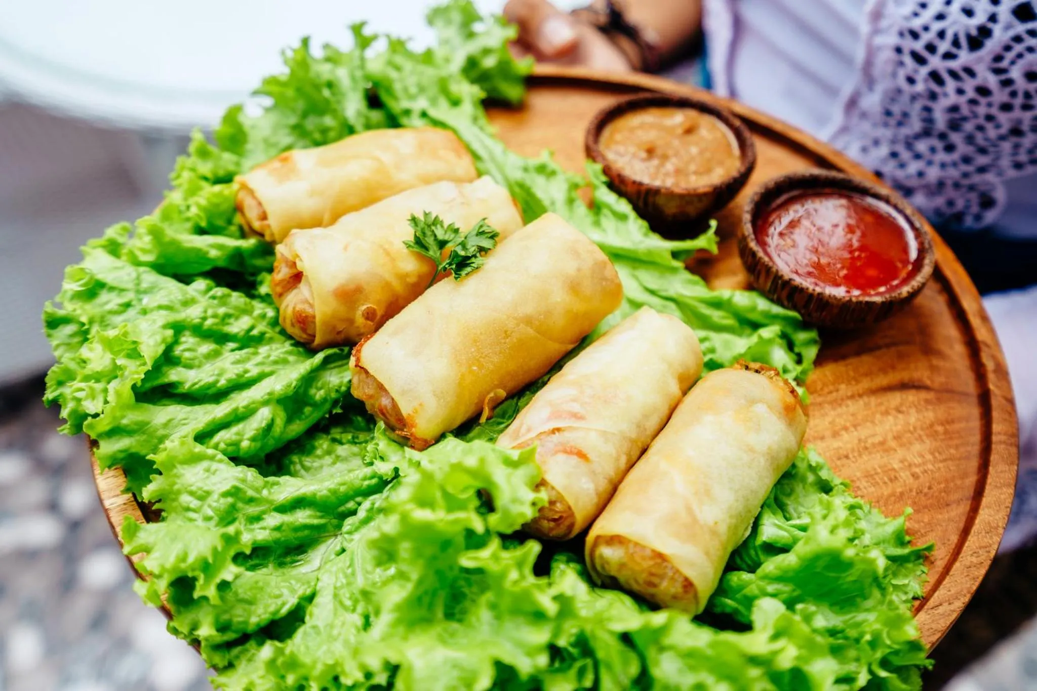 Assiette de rouleaux de printemps servis sur un plateau en bois avec des sauces.