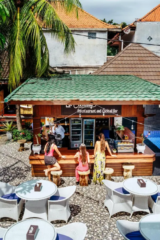Un bar en plein air avec des clients debout devant le comptoir.