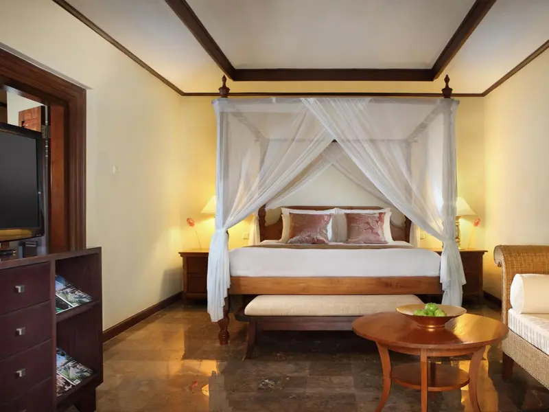 Une chambre lumineuse avec un grand lit à baldaquin et un coin salon.