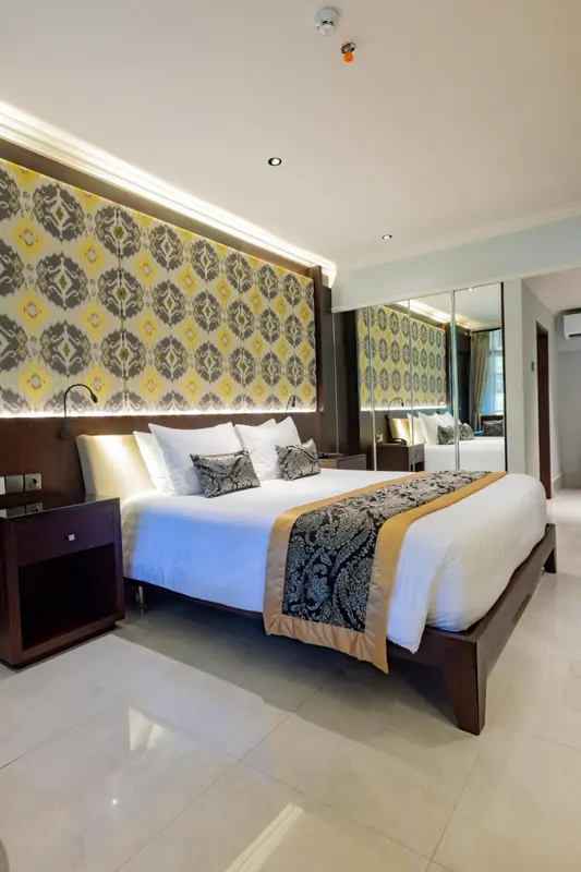 Une chambre lumineuse avec un grand lit recouvert d'une couette blanche et de coussins décoratifs.