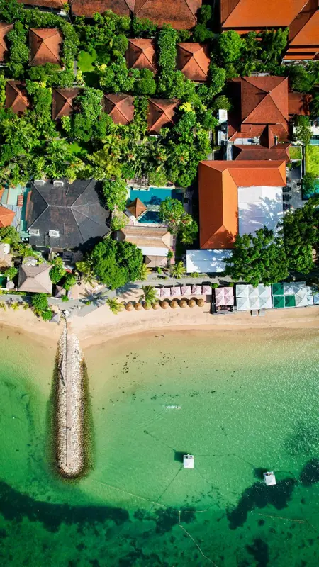 Vue aérienne d'un complexe hôtelier bordant une plage de sable fin et une mer turquoise.