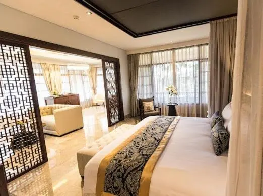 Une chambre lumineuse avec un grand lit et un espace salon.