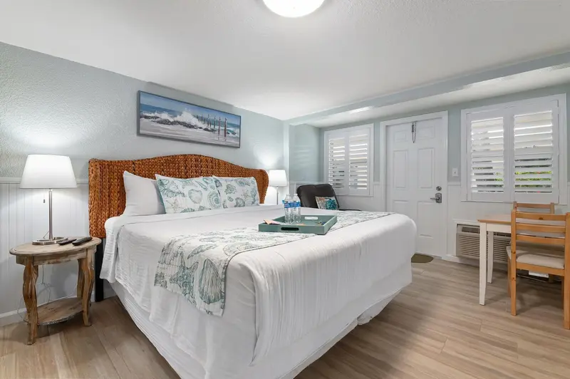 Une chambre lumineuse avec un grand lit et un coin repas.