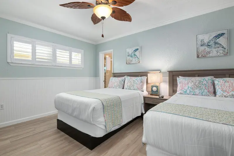 Chambre lumineuse avec deux lits jumeaux et décoration marine.
