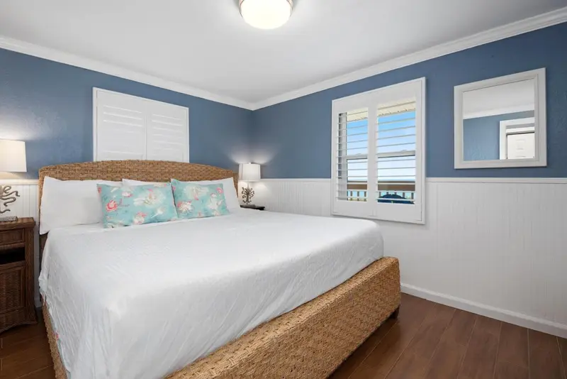 Une chambre lumineuse avec un grand lit recouvert de blanc.
