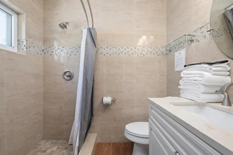 Une douche à l'italienne et des serviettes pliées sur un meuble.
