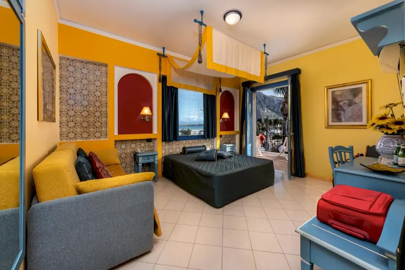 Une chambre lumineuse avec un lit et un canapé, donnant sur une vue mer.