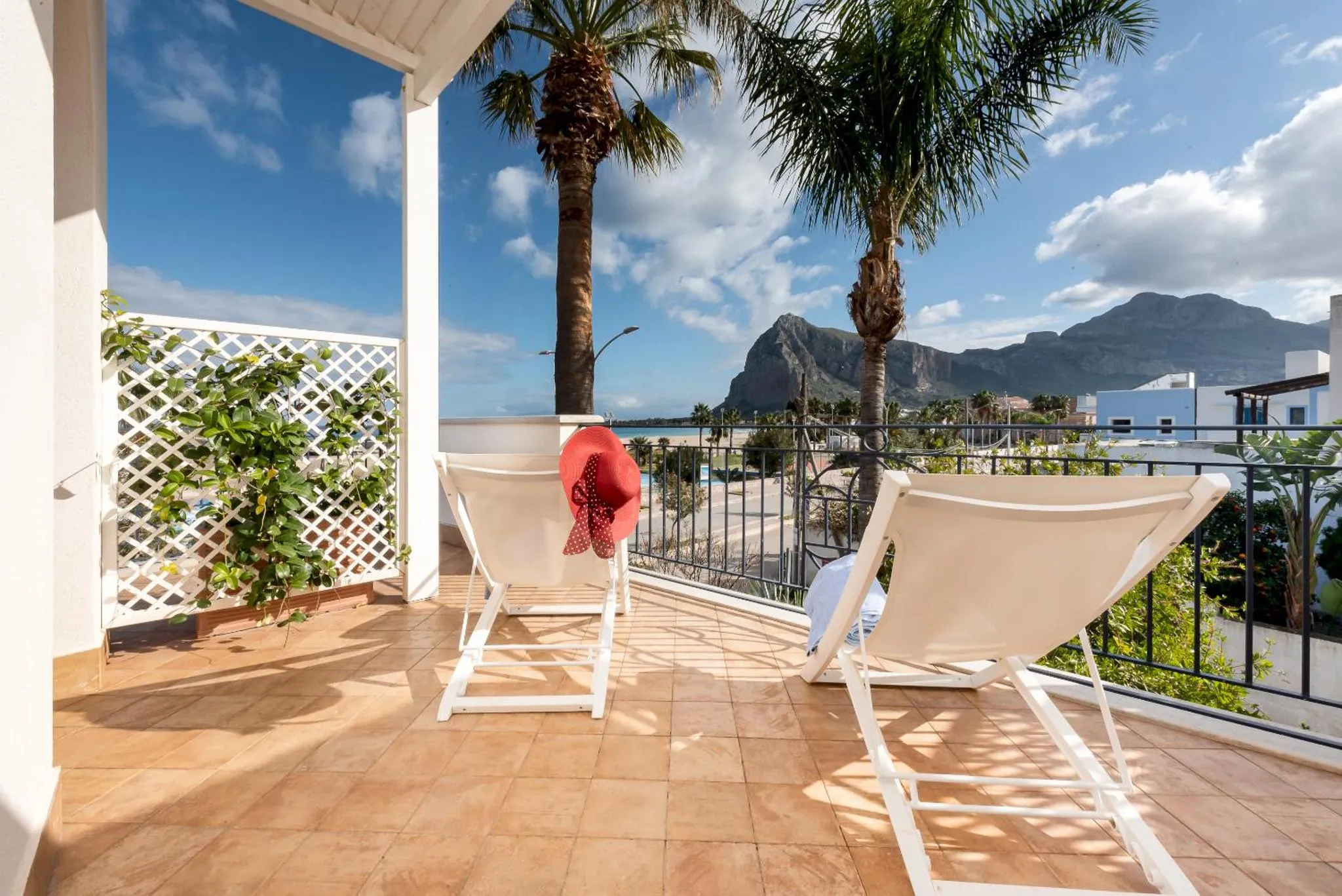 Deux transats blancs sur une terrasse carrelée avec vue sur la mer et les montagnes.