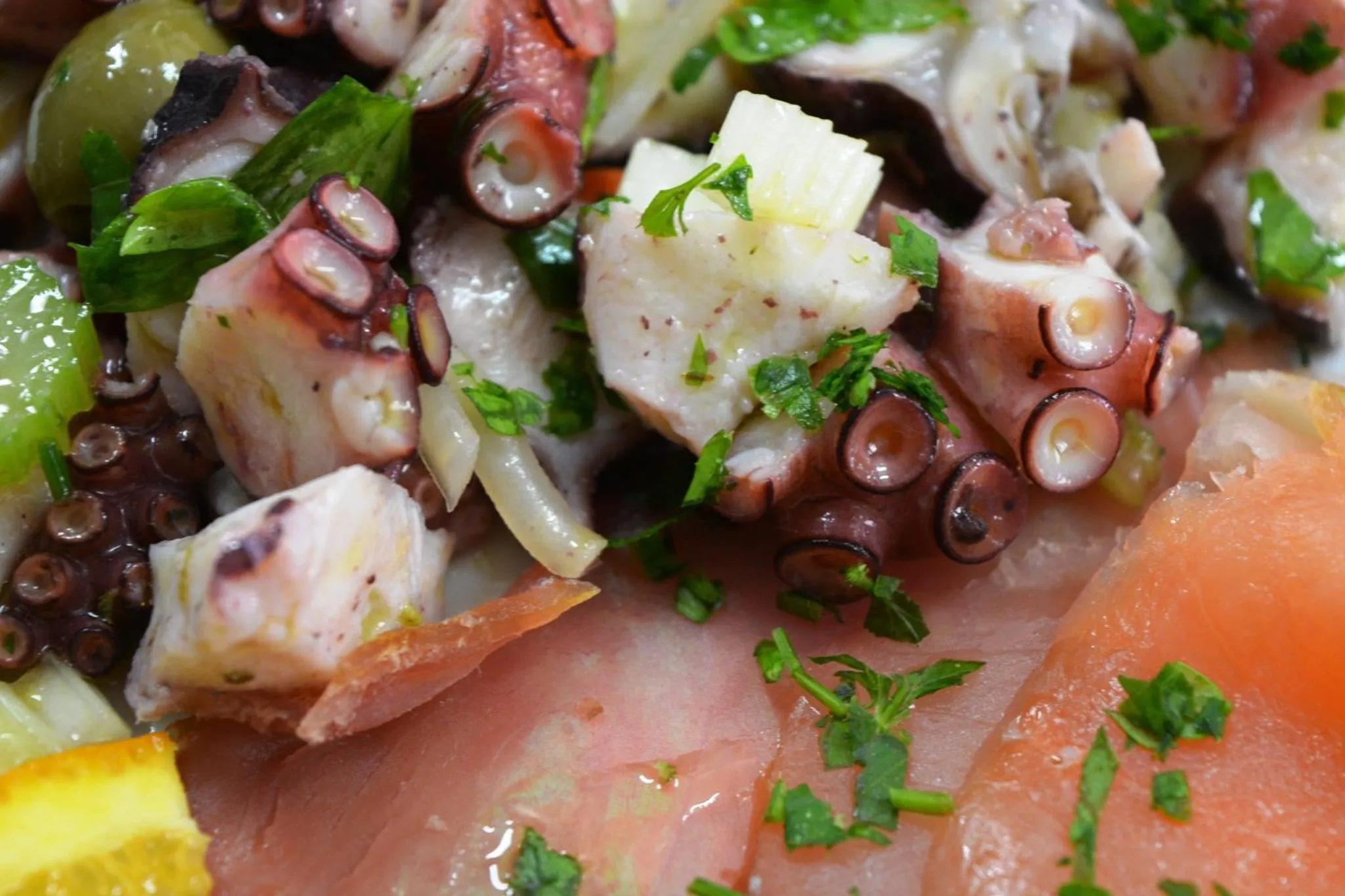 Salade de poulpe et de saumon, agrémentée de persil et de citron.