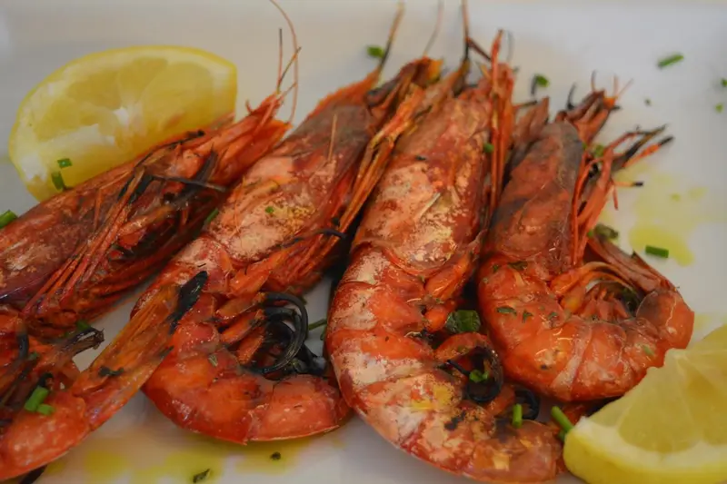 Assiette de crevettes grillées garnies de citron et d'herbes fraîches.