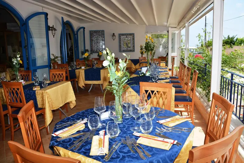 Une salle à manger lumineuse avec des tables dressées pour le service.