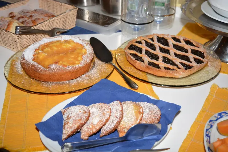 Assortiment de pâtisseries et viennoiseries sur une table recouverte d'une nappe colorée.