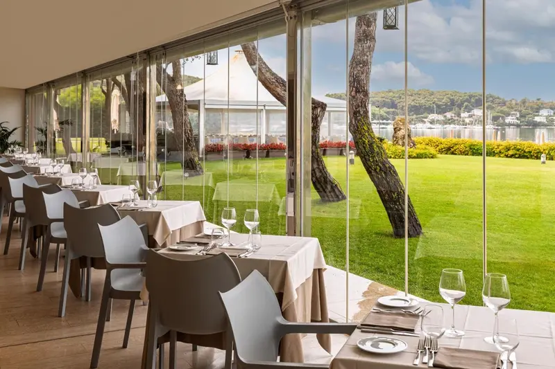 Une salle à manger lumineuse donne sur un jardin verdoyant et la mer.