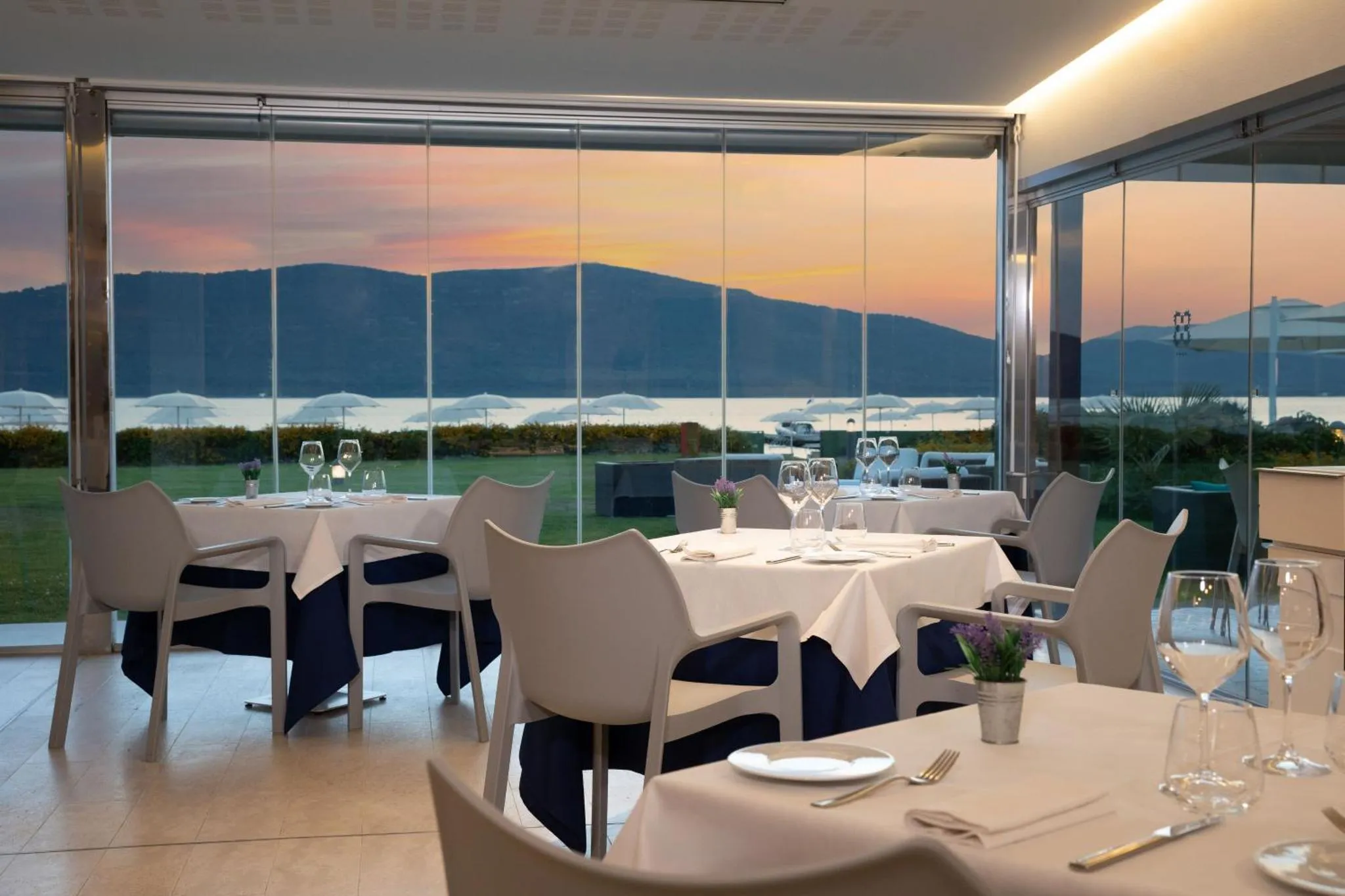 Une salle à manger lumineuse offre une vue sur la mer et un coucher de soleil orangé.