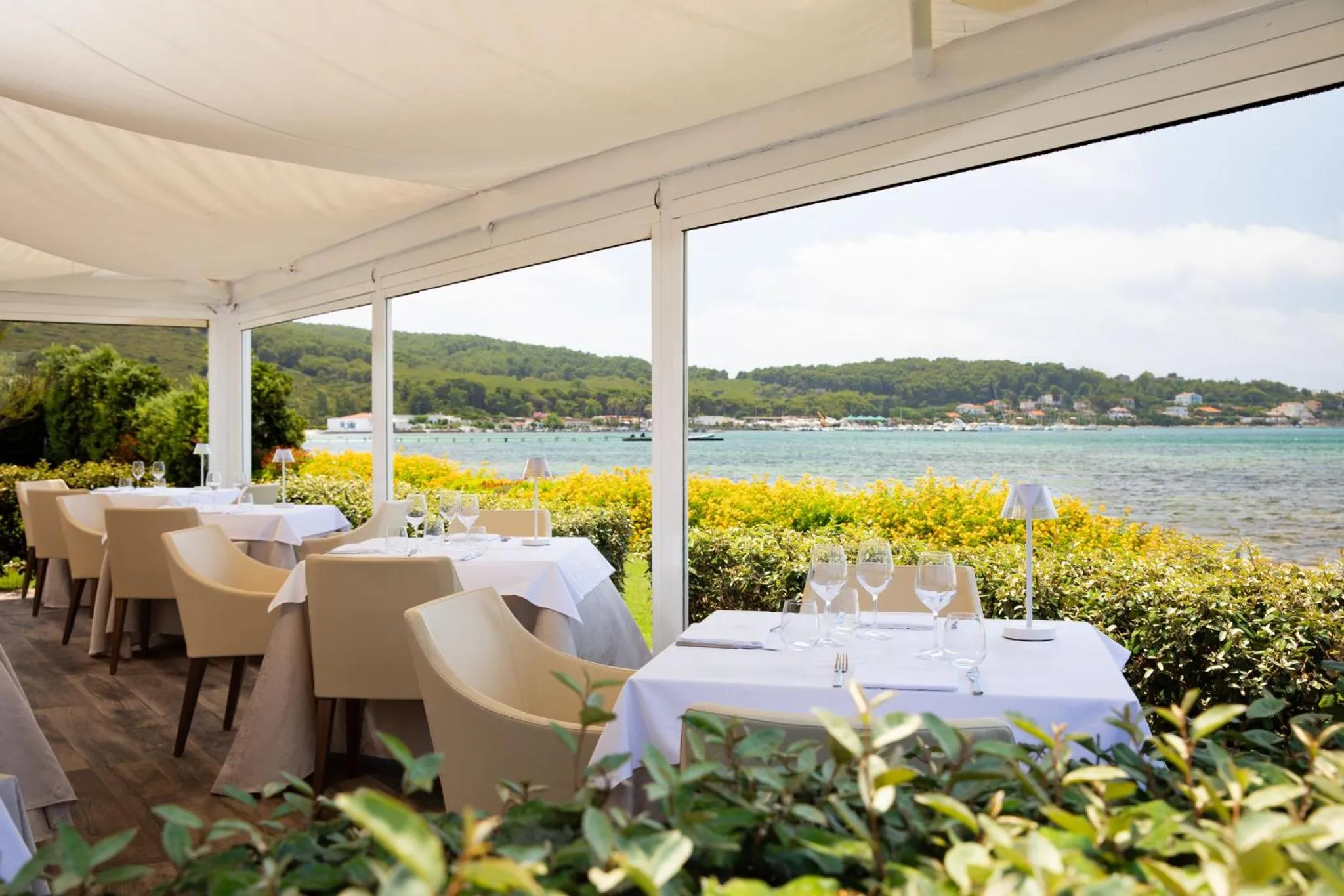 Une terrasse de restaurant offre une vue sur la mer et la végétation.