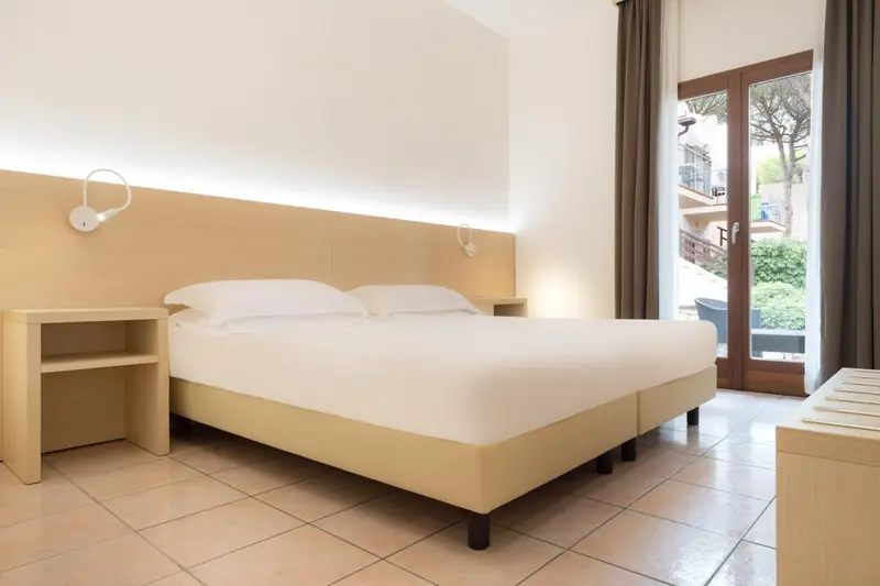 Une chambre lumineuse avec un grand lit et un accès à un balcon.