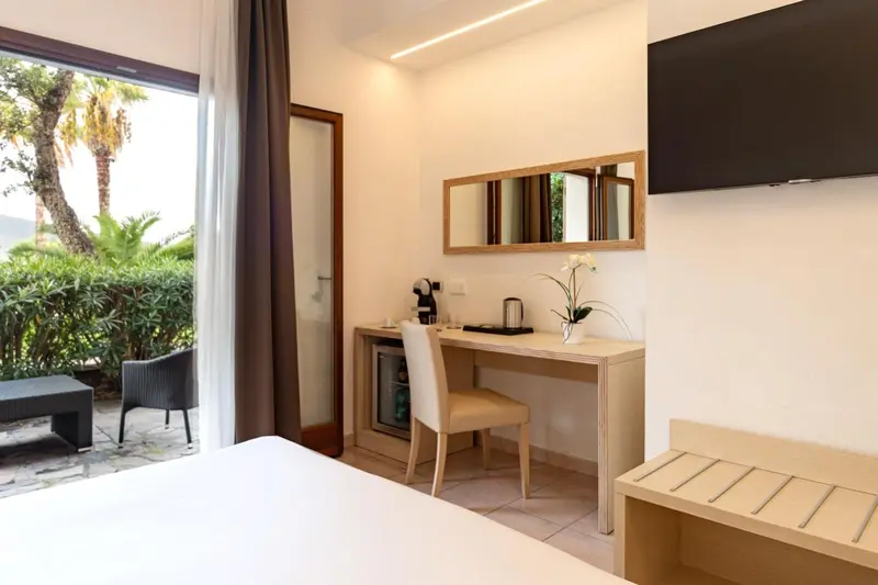 Une chambre lumineuse avec un bureau et une vue sur la végétation.