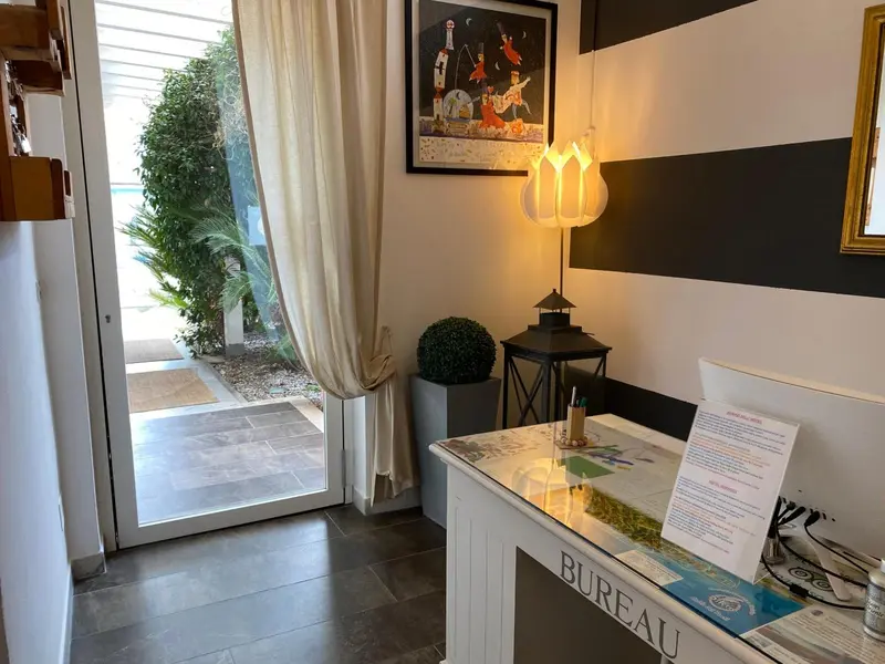 Une réception lumineuse s'ouvre sur une terrasse ensoleillée et une vue sur la mer.