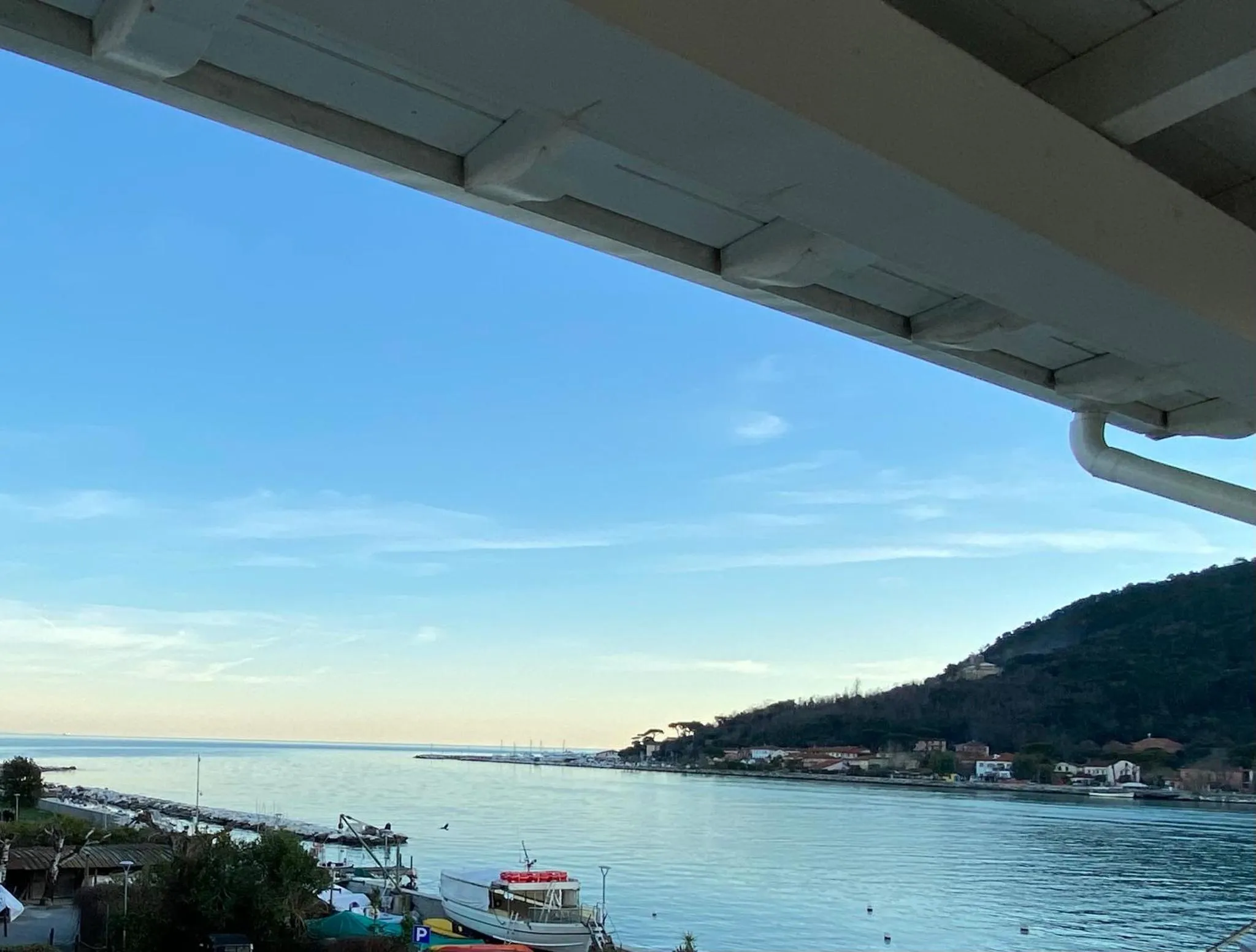 Vue sur la mer et la côte depuis un balcon ombragé.