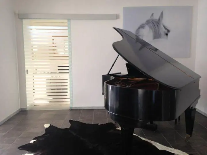 Un piano à queue noir se trouve dans un espace intérieur minimaliste.