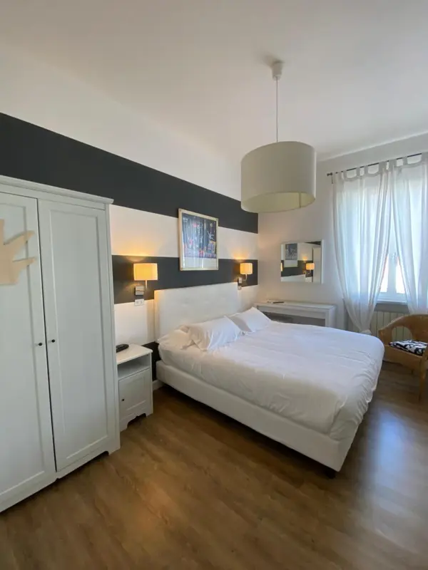 Une chambre lumineuse avec un grand lit blanc et une décoration moderne.