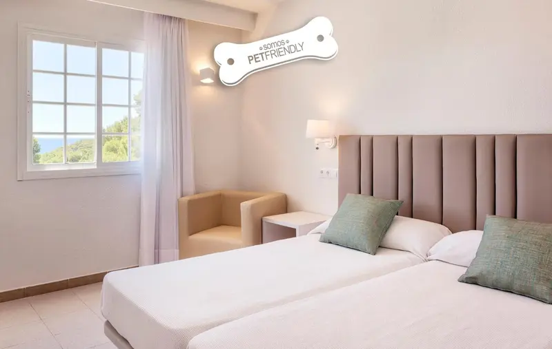 Une chambre lumineuse avec un lit double et un fauteuil.