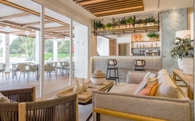 Espace de détente intérieur avec canapés et comptoir de bar en fond.