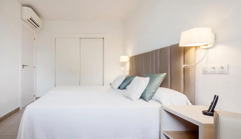 Une chambre lumineuse avec un grand lit recouvert de draps blancs.