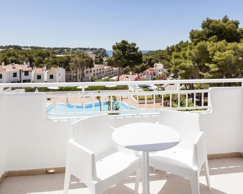 Terrasse avec mobilier blanc donnant sur une piscine et un paysage verdoyant.