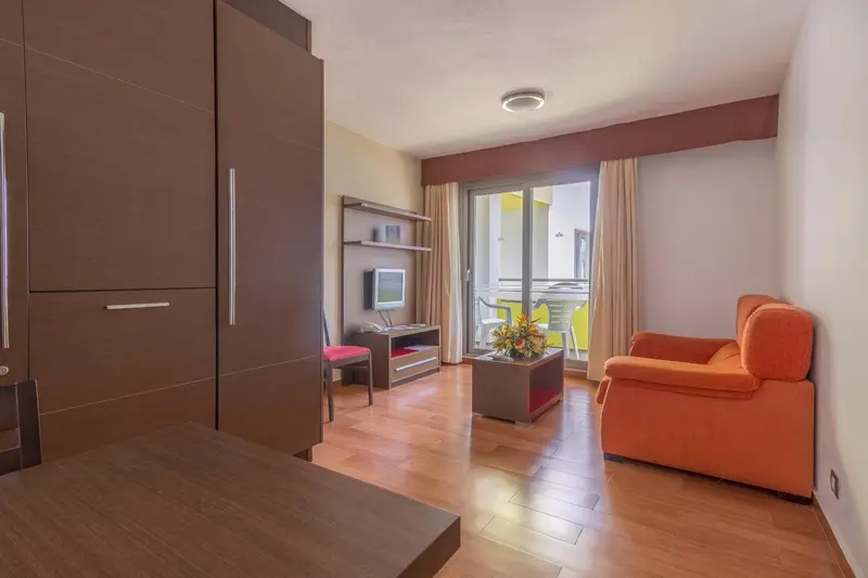 Espace de séjour lumineux avec canapé orange et télévision.