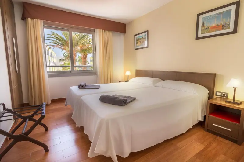 Une chambre lumineuse avec un grand lit et une vue sur la végétation.
