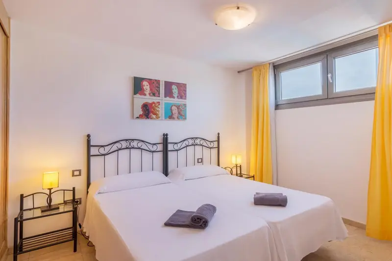Une chambre lumineuse avec un lit double et des rideaux jaunes.