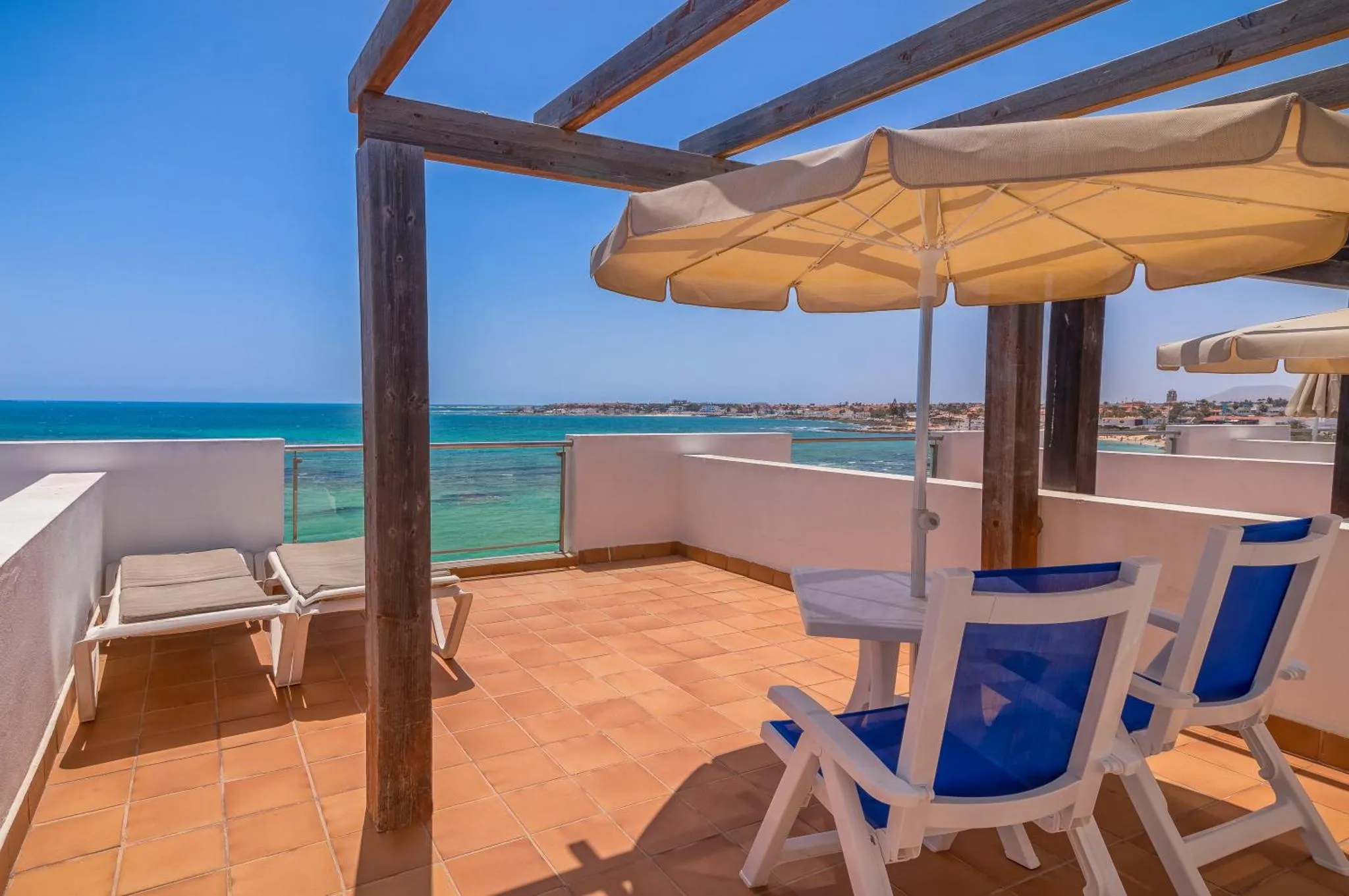Terrasse carrelée avec mobilier de jardin et vue sur la mer.