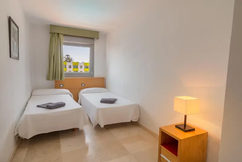 Une chambre lumineuse avec deux lits simples et une fenêtre.