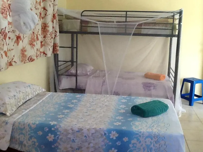 Une chambre avec un lit simple et un lit superposé recouvert de moustiquaires.