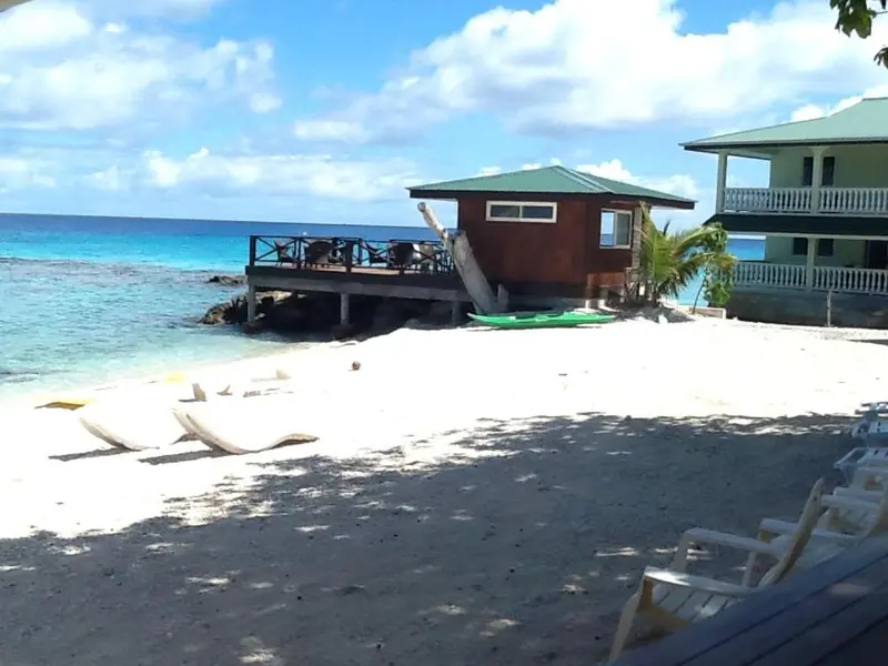 Plage de sable fin bordée d'une mer turquoise et de quelques bungalows.