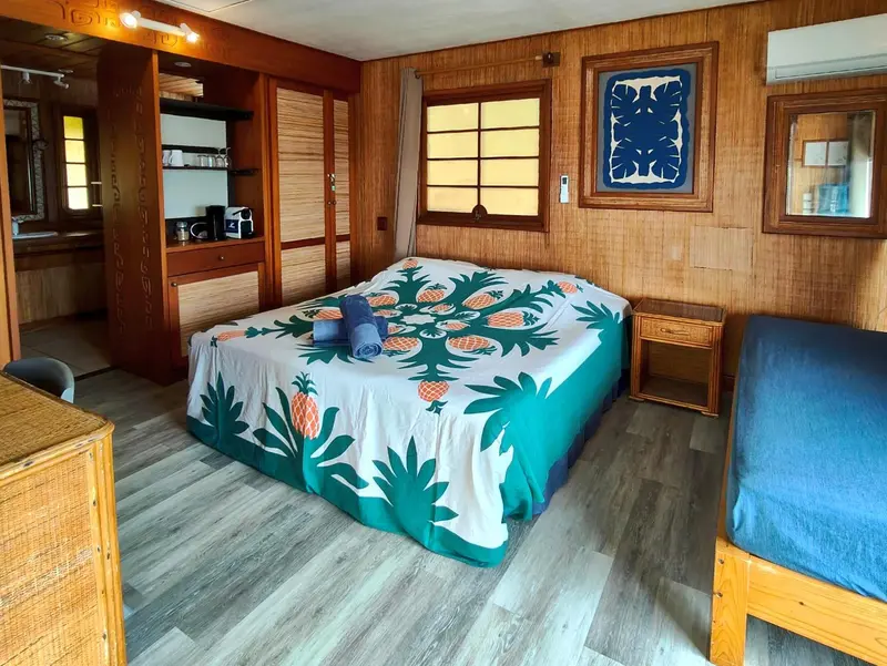 Une chambre lumineuse avec un lit recouvert d'une courtepointe à motifs tropicaux.