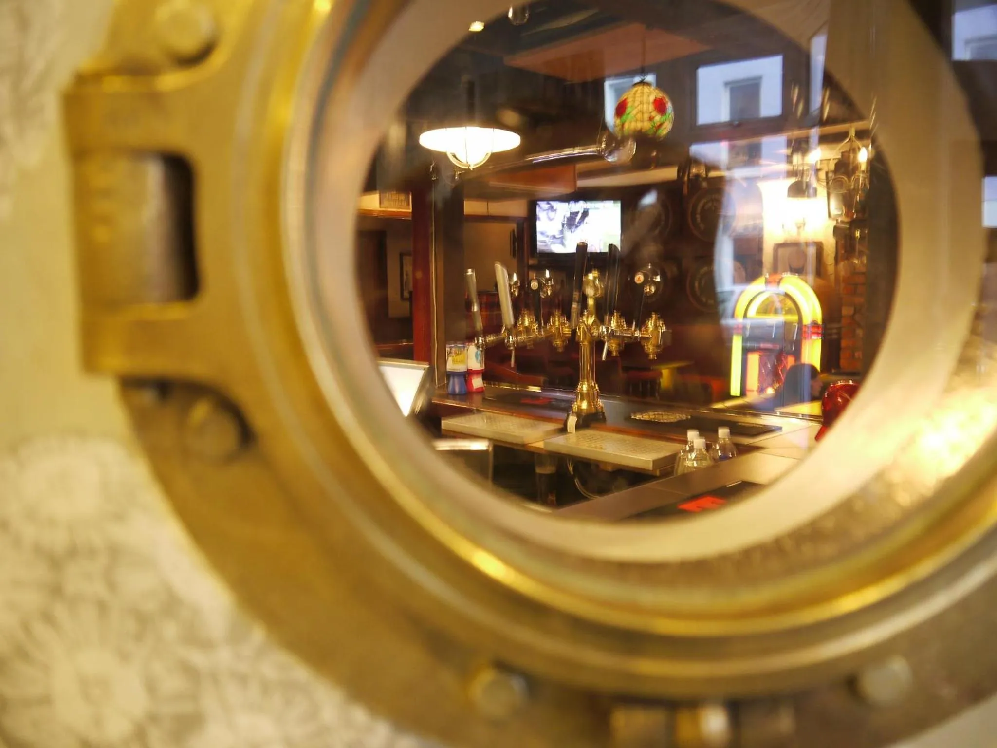Un comptoir de bar est visible à travers un hublot doré.