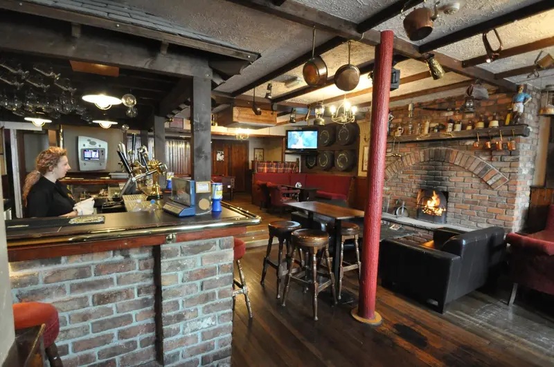 Un bar chaleureux avec un comptoir en briques et une cheminée allumée.