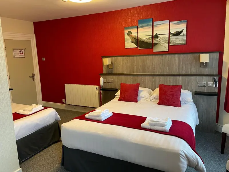 Une chambre d'hôtel avec un lit double et un lit simple, décorée de couleurs vives.