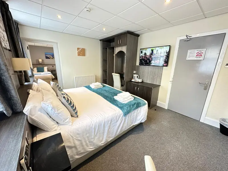 Une chambre lumineuse avec un grand lit recouvert d'une courtepointe turquoise et de coussins.