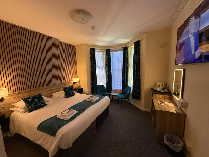 Une chambre d'hôtel lumineuse avec un grand lit et deux fauteuils.