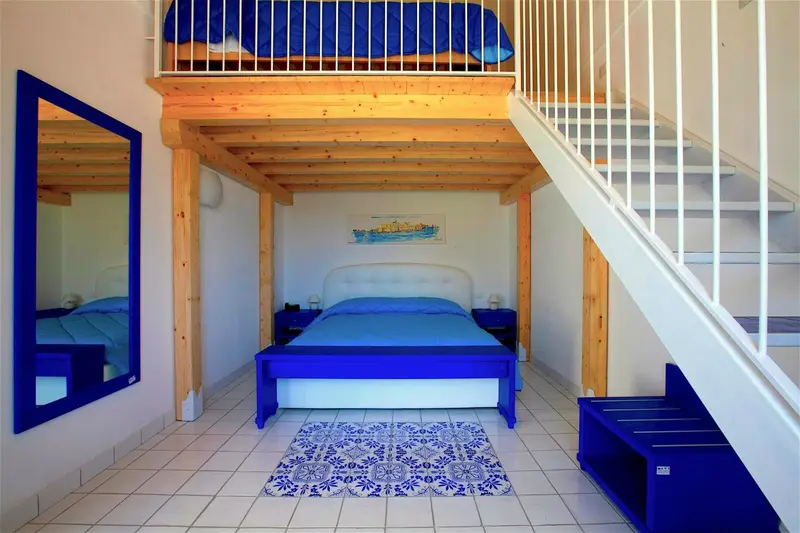 Une chambre avec un lit superposé et un escalier en bois.