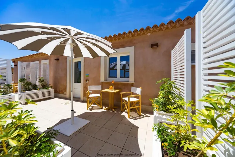 Terrasse carrelée avec parasol rayé et mobilier de jardin.