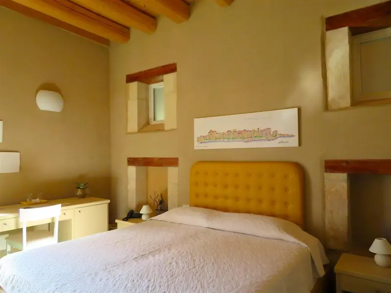 Une chambre lumineuse avec un lit jaune et des murs en pierre.