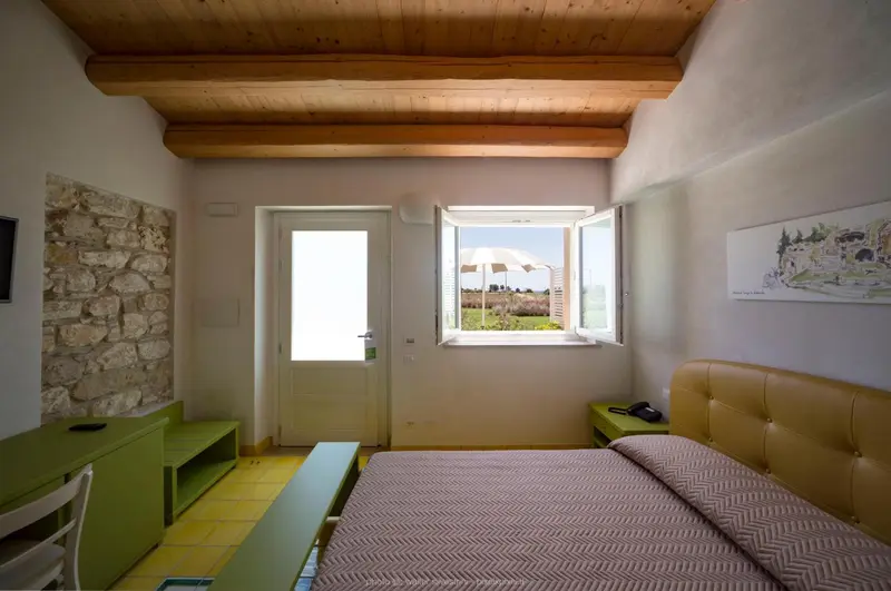 Une chambre lumineuse avec un lit et une fenêtre ouverte sur un paysage.