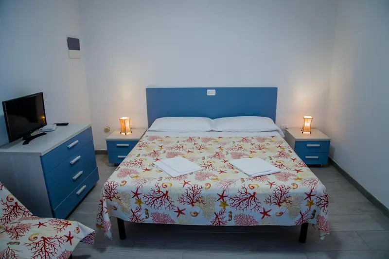 Une chambre lumineuse avec un grand lit recouvert d'une courtepointe colorée.