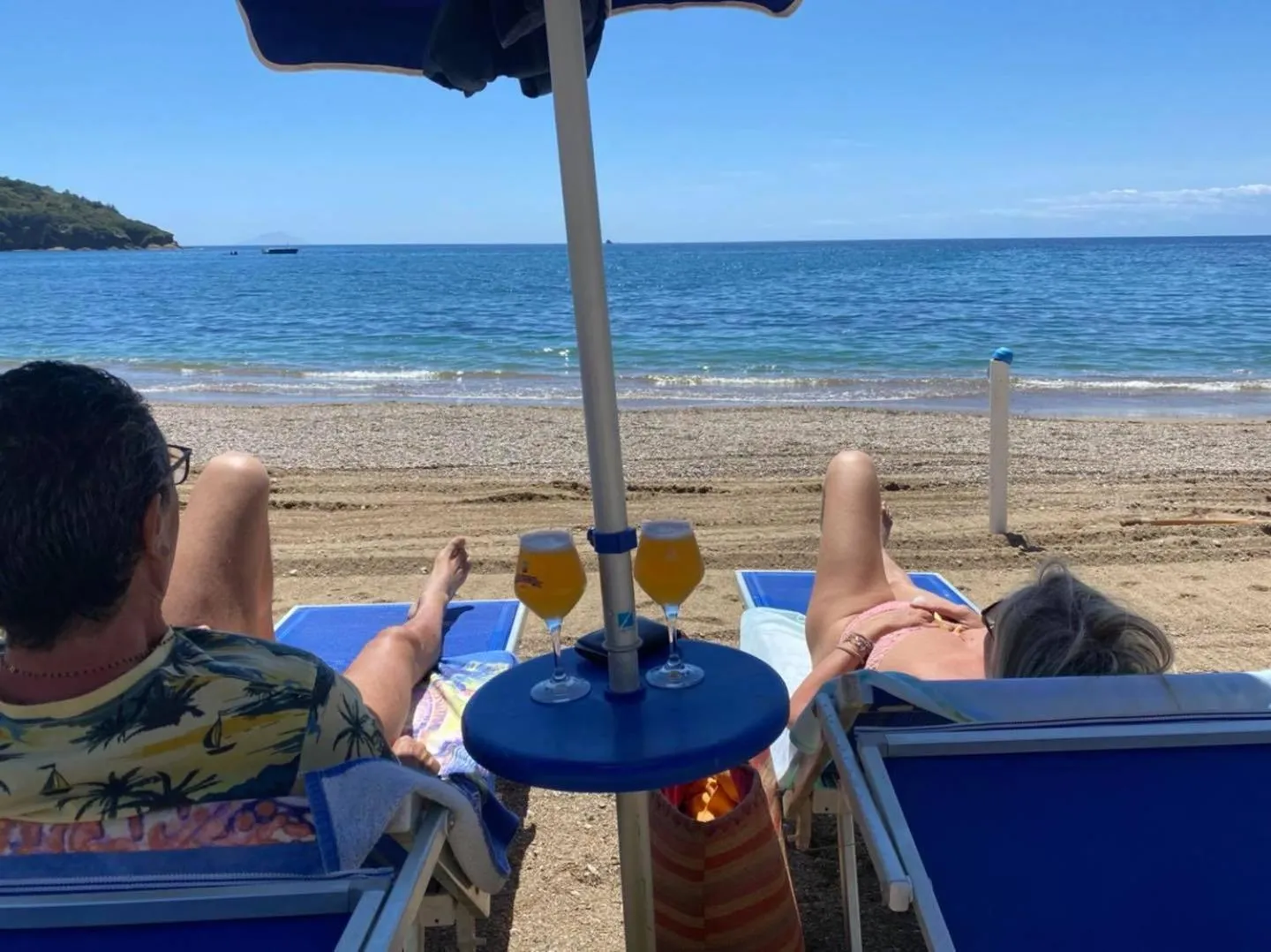 Deux personnes se détendent sur des transats face à la mer.