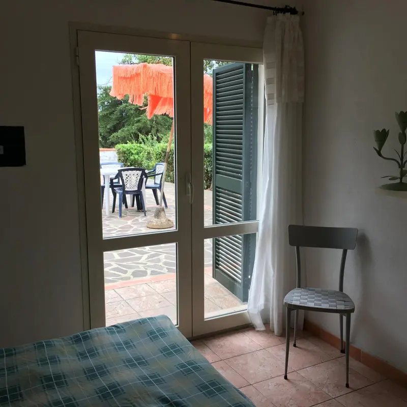 Une chambre s'ouvre sur une terrasse avec mobilier de jardin.