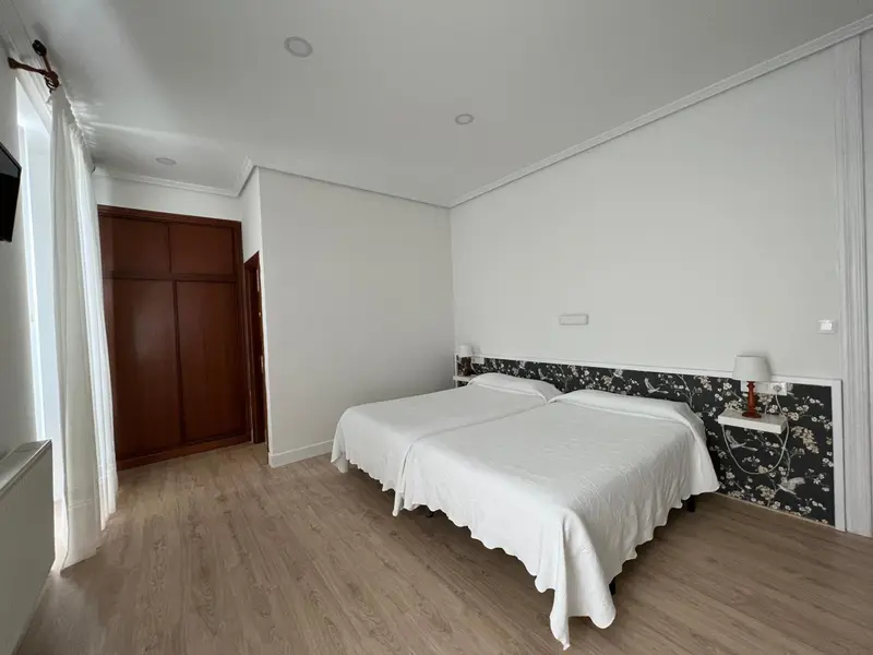 Chambre lumineuse avec un grand lit et une décoration sobre.